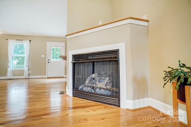 unfurnished living room with hardwood / wood-style floors and a towering ceiling