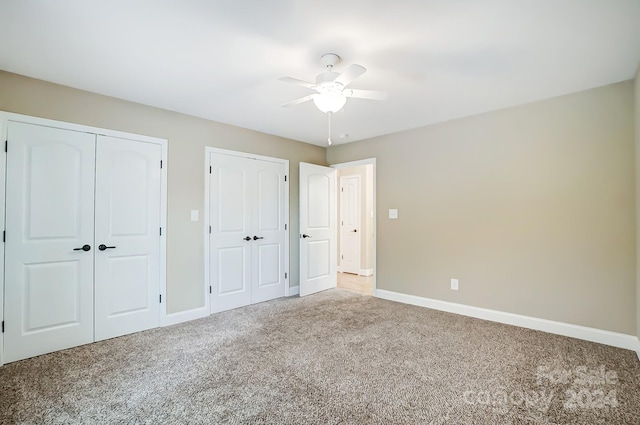 unfurnished bedroom with ceiling fan, carpet floors, and two closets