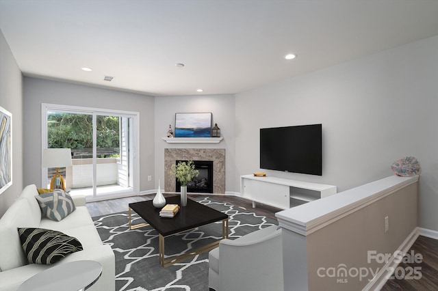 living room with a tiled fireplace and wood-type flooring