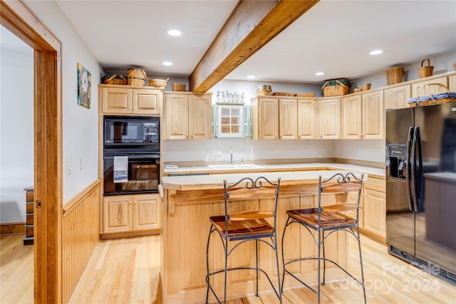 kitchen with a center island, sink, light wood-type flooring, beam ceiling, and black appliances