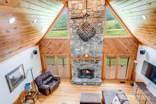 living room with plenty of natural light, light hardwood / wood-style flooring, wooden walls, and a fireplace