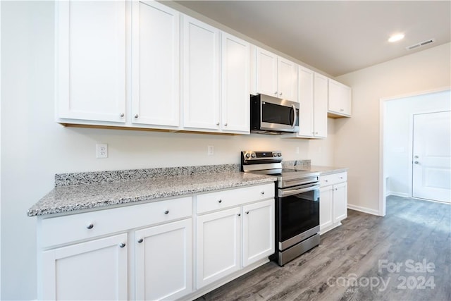 kitchen with appliances with stainless steel finishes, light stone counters, light hardwood / wood-style flooring, and white cabinets