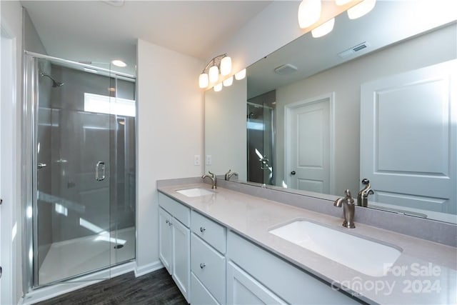 bathroom with wood-type flooring, vanity, and a shower with shower door