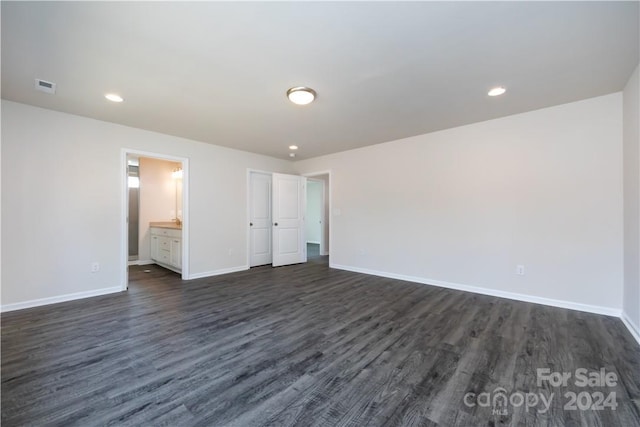 unfurnished bedroom featuring ensuite bathroom and dark wood-type flooring