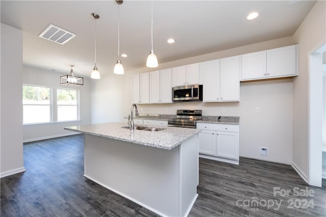 kitchen with a center island with sink, sink, stainless steel appliances, hanging light fixtures, and white cabinetry