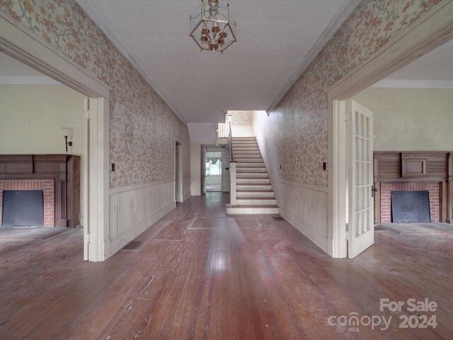 hall with crown molding, an inviting chandelier, and wood-type flooring