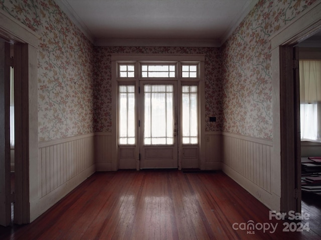 spare room with dark wood-style floors, wainscoting, ornamental molding, and wallpapered walls