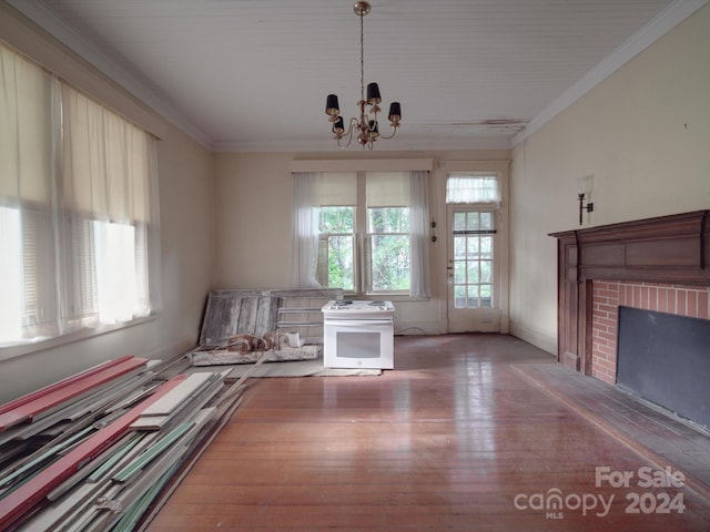 interior space with ornamental molding, a brick fireplace, light wood-style flooring, and a notable chandelier