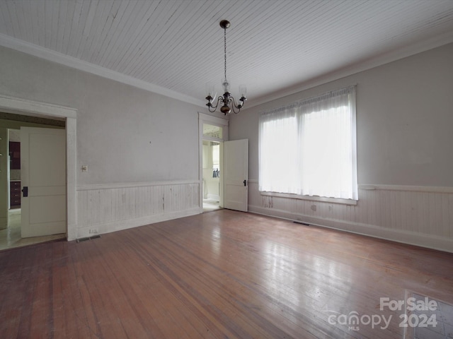 interior space with a chandelier, a wainscoted wall, wood finished floors, visible vents, and crown molding