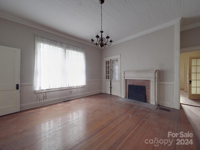 unfurnished living room with a fireplace, wainscoting, wood finished floors, and visible vents