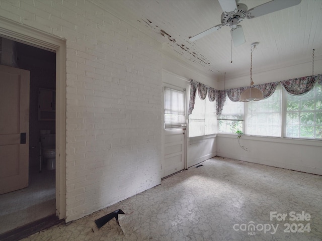 empty room featuring brick wall and ceiling fan