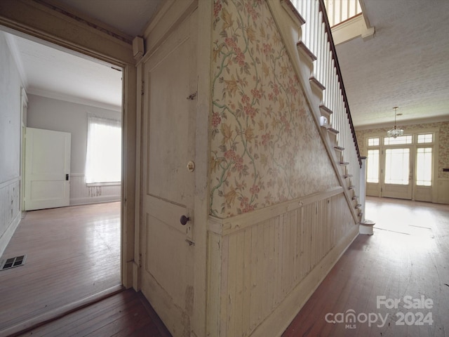 hall with stairway, visible vents, wood finished floors, and wainscoting