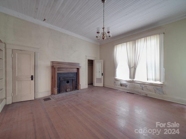 unfurnished living room with visible vents, an inviting chandelier, ornamental molding, a fireplace with flush hearth, and wood finished floors