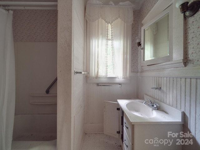 bathroom featuring wallpapered walls, vanity, and wainscoting