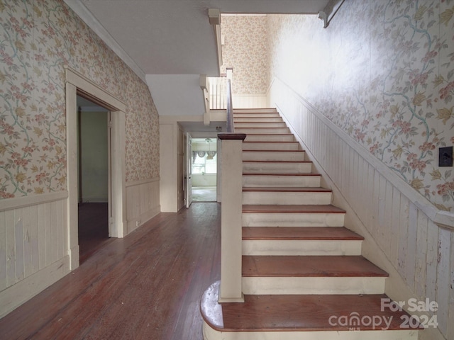 stairway featuring wood finished floors, wainscoting, and wallpapered walls