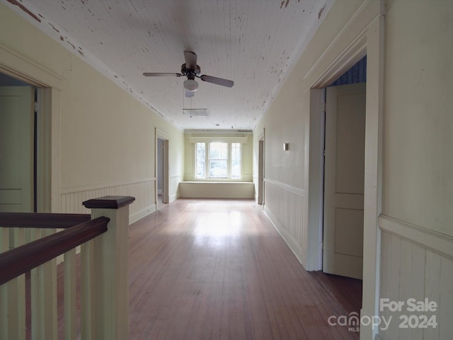 hall with a wainscoted wall, visible vents, and wood finished floors