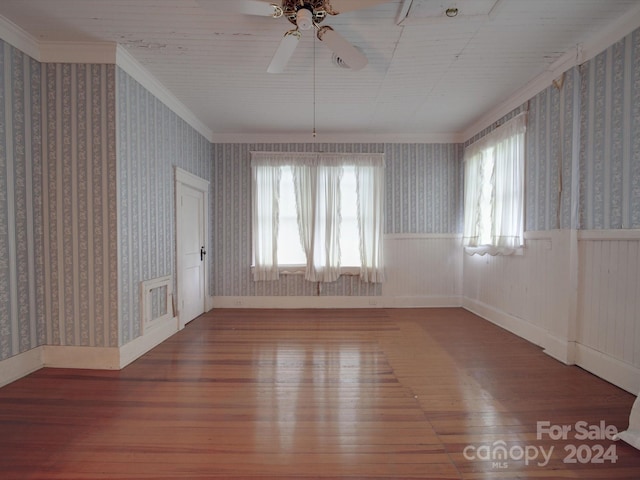 spare room featuring ornamental molding, wood finished floors, wainscoting, and wallpapered walls