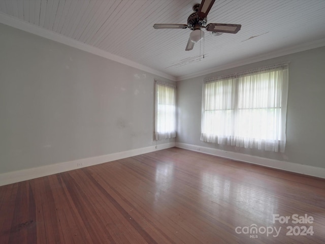 spare room with ornamental molding, wood finished floors, a ceiling fan, and baseboards