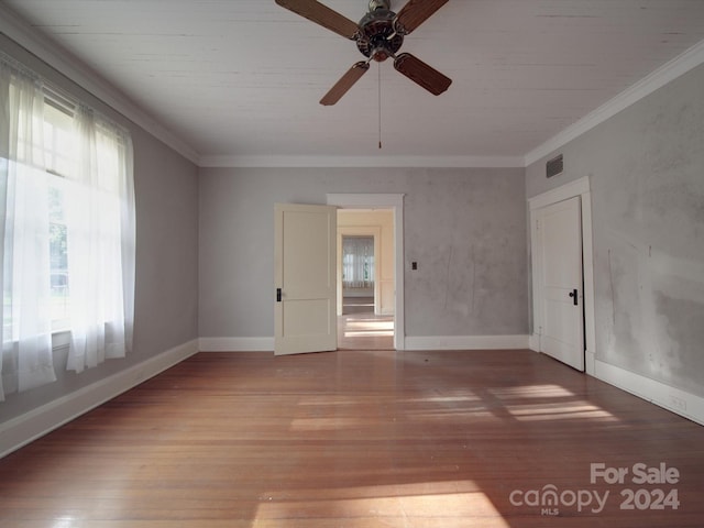 unfurnished room featuring crown molding, visible vents, baseboards, and wood finished floors