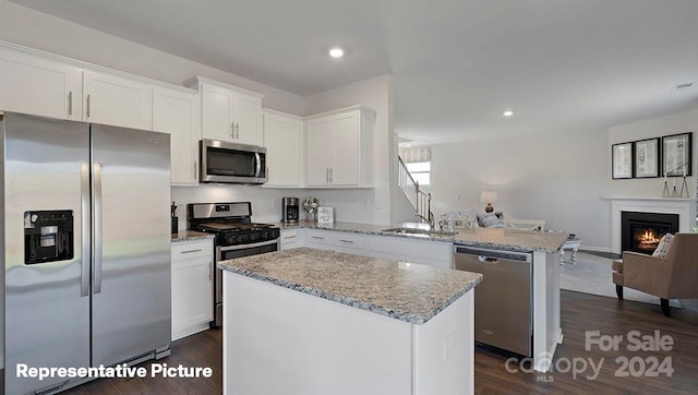 kitchen featuring appliances with stainless steel finishes, white cabinets, a center island, and dark hardwood / wood-style floors