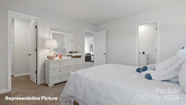 bedroom with ensuite bathroom and light colored carpet