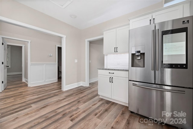 kitchen featuring white cabinetry, stainless steel fridge with ice dispenser, light hardwood / wood-style floors, and light stone counters