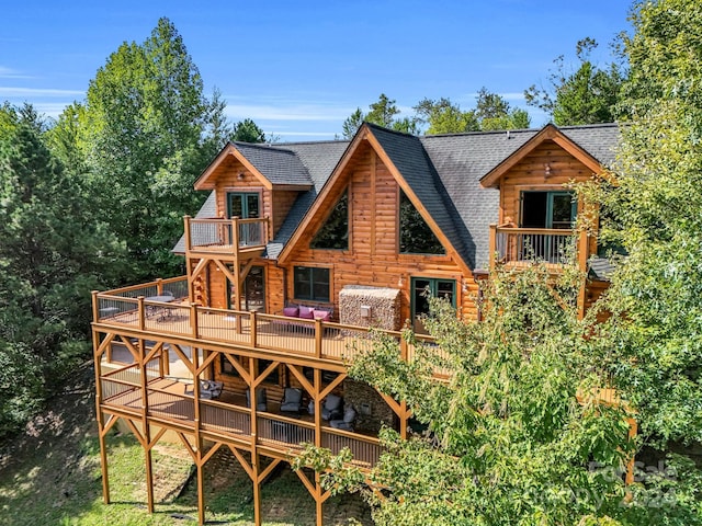 rear view of property featuring a shingled roof and a balcony