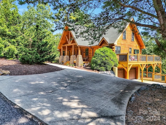 log-style house featuring a garage, driveway, roof with shingles, and log siding