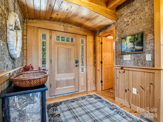 interior space with wood walls, wood-type flooring, vaulted ceiling, and wooden ceiling