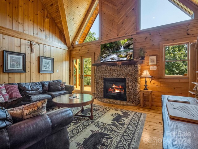 living room featuring light wood-type flooring, wood walls, high vaulted ceiling, and wooden ceiling