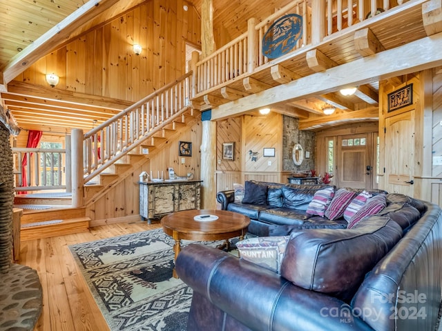 living room with light hardwood / wood-style flooring, wooden walls, beamed ceiling, and a healthy amount of sunlight