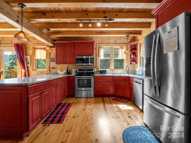 kitchen with stainless steel appliances, wood walls, beam ceiling, and light wood-style floors