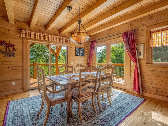 dining space with wooden walls and beamed ceiling