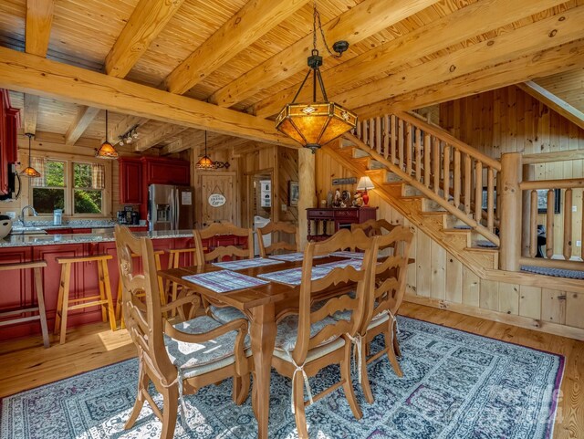 dining space with wood walls, hardwood / wood-style flooring, lofted ceiling with beams, and wooden ceiling