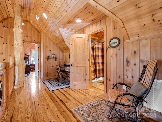 unfurnished room featuring lofted ceiling, light wood-style floors, wood ceiling, and wooden walls