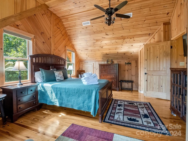 bedroom with ceiling fan, wood walls, wood-type flooring, and multiple windows