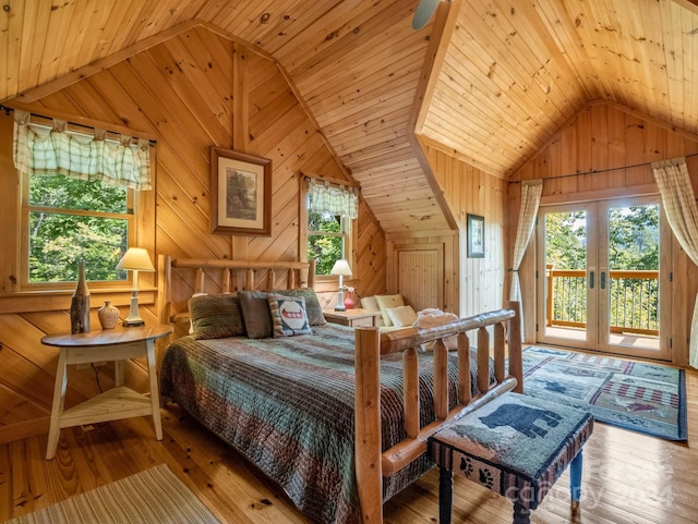 bedroom with lofted ceiling, wood walls, and multiple windows