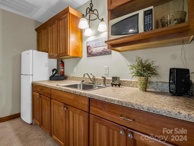 kitchen with sink, light colored carpet, and white fridge