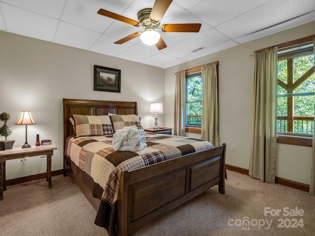 bedroom with light carpet, a ceiling fan, baseboards, and a drop ceiling