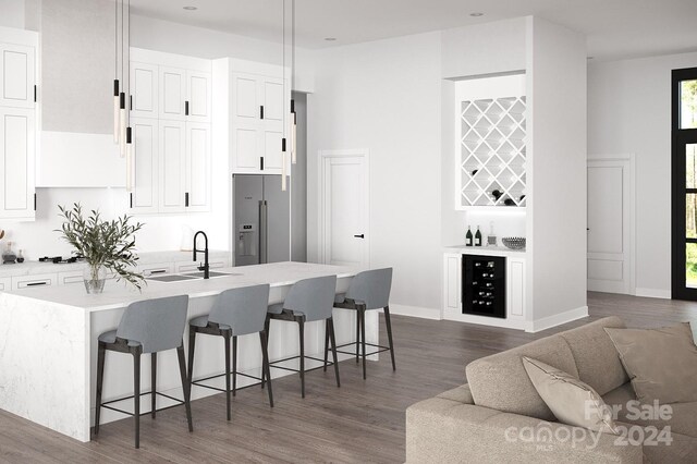 kitchen featuring sink, a center island with sink, high quality fridge, a breakfast bar area, and dark wood-type flooring