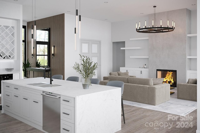 kitchen with light hardwood / wood-style floors, a multi sided fireplace, hanging light fixtures, and white cabinetry