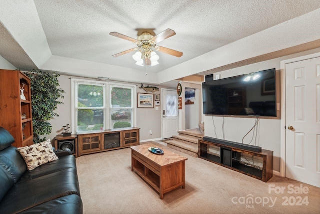 living room featuring a tray ceiling, ceiling fan, a textured ceiling, and light carpet