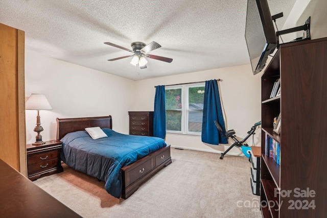 carpeted bedroom with ceiling fan and a textured ceiling