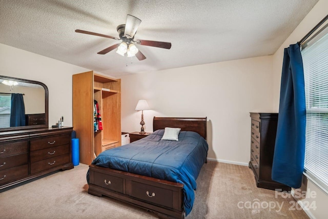 bedroom with light colored carpet, a textured ceiling, multiple windows, and ceiling fan