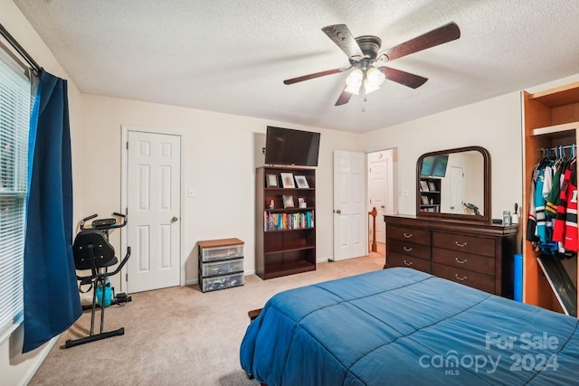 bedroom featuring a textured ceiling, ceiling fan, and light colored carpet