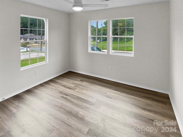 unfurnished room with ceiling fan, wood-type flooring, and a wealth of natural light