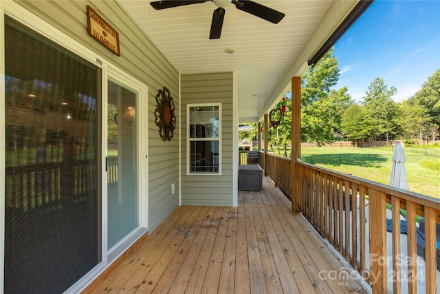 wooden deck featuring a lawn and ceiling fan