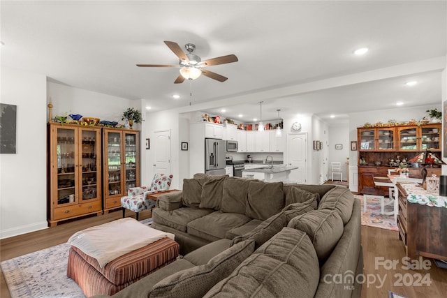 living room with ceiling fan, sink, and hardwood / wood-style floors