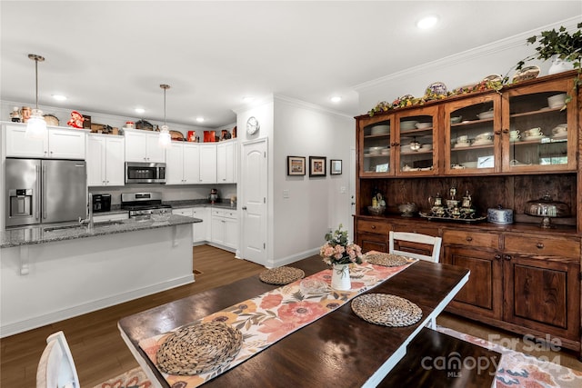 dining space featuring sink, dark wood-type flooring, and ornamental molding