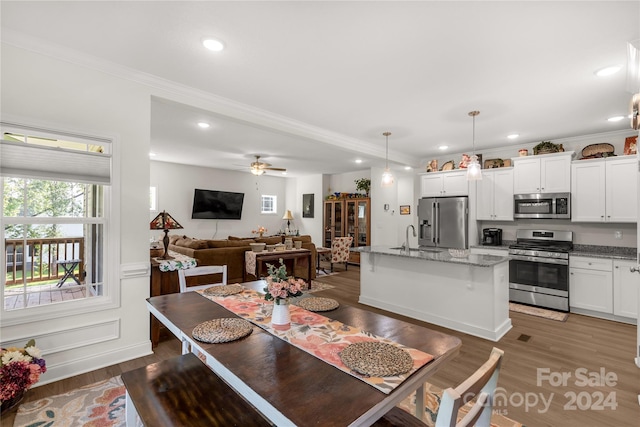 dining room with ceiling fan, sink, ornamental molding, and dark hardwood / wood-style flooring